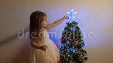 儿童圣诞假期快乐概念。 孩子在节日<strong>树</strong>上检查<strong>一颗</strong>圣诞星。 小女孩在附近玩耍